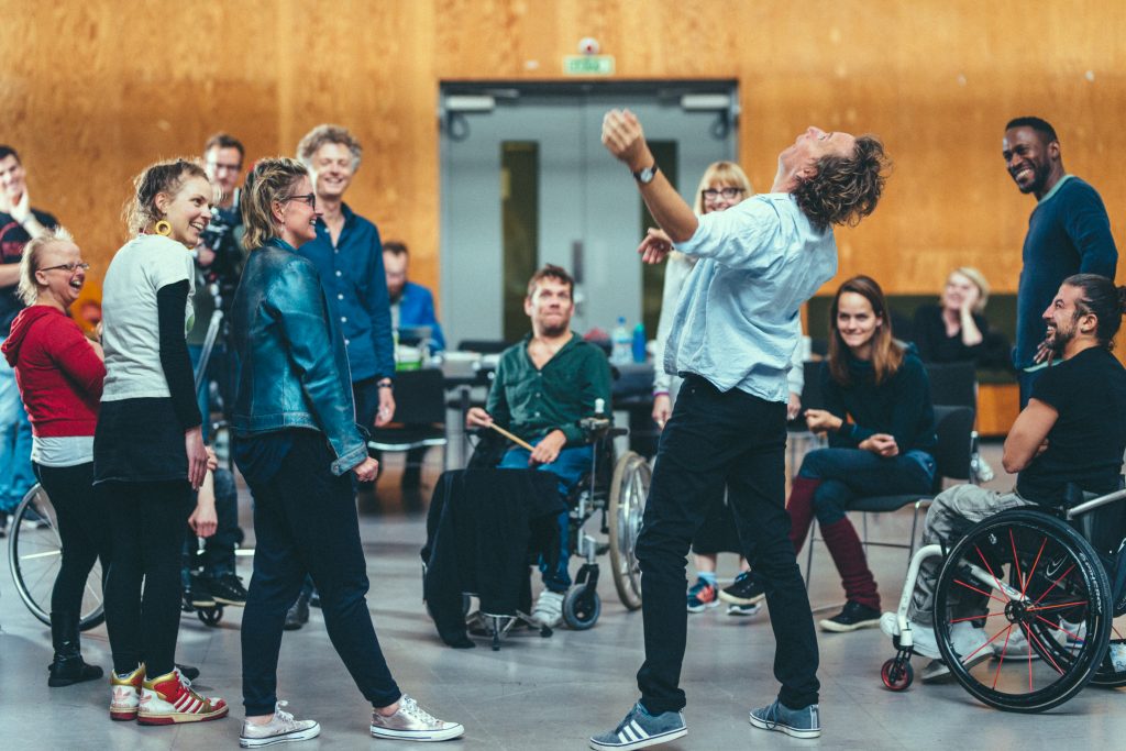 Extraordinary Bodies Artists and Creative Team in residency at National Theatre Studios, moving and laughing in the room, watching Ted Barnes dance in the middle of the room.
