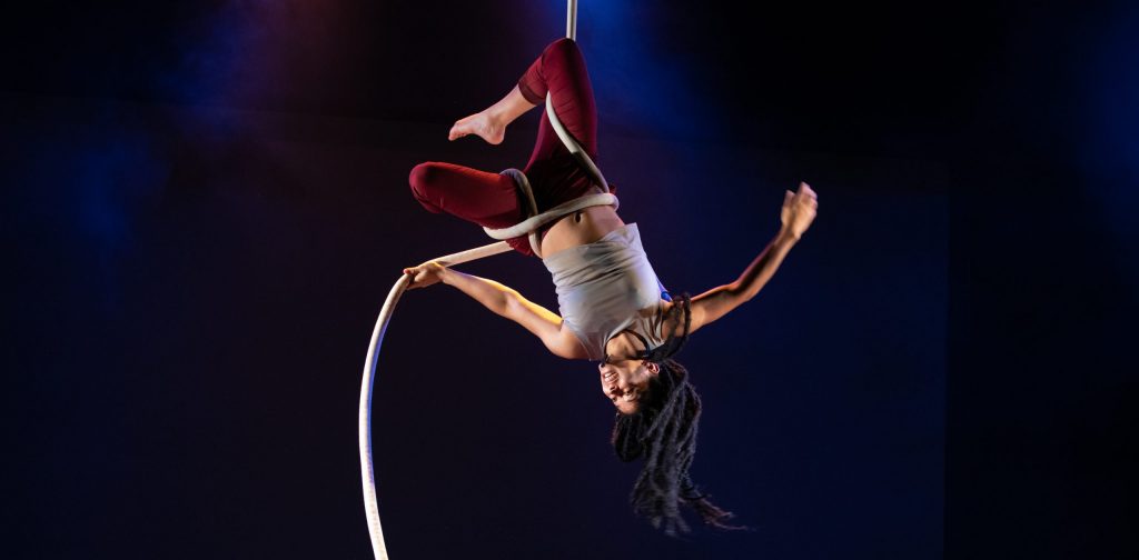 An aerial artists spins upside down