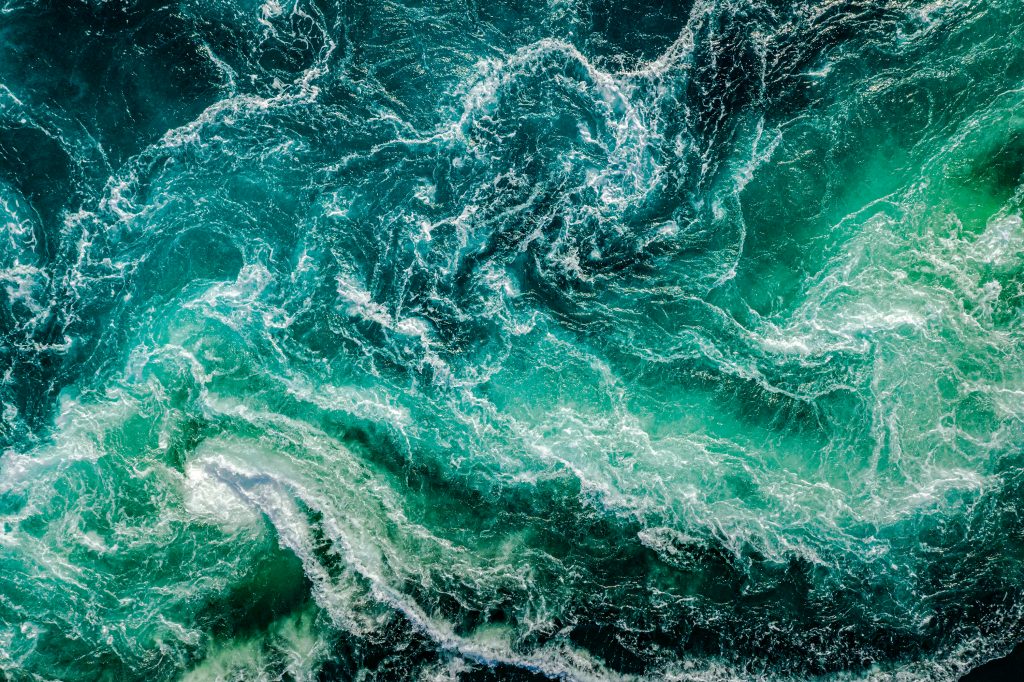 A photograph of a turbulent sea, shot from above on a sunny day.